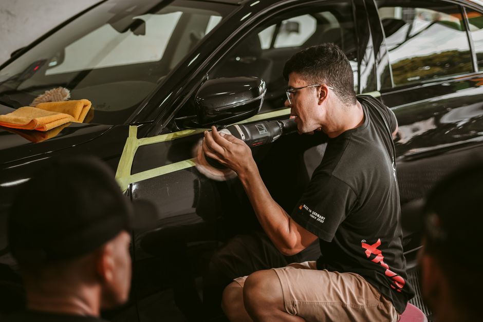 Professional auto detailer carefully drying a vehicle by hand